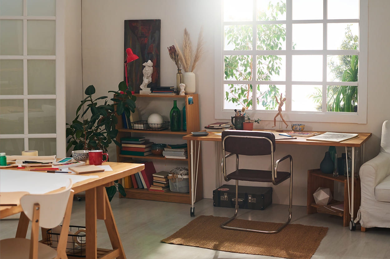 Photo of a bright share house living room with a desk, table, bookcase and other items.