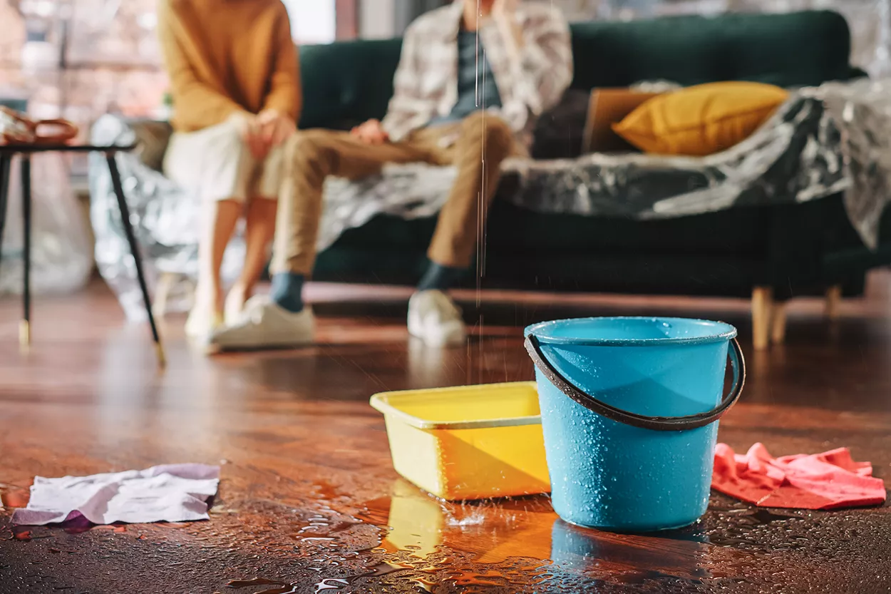 Photo of blue and yellow buckets catching leaking water.