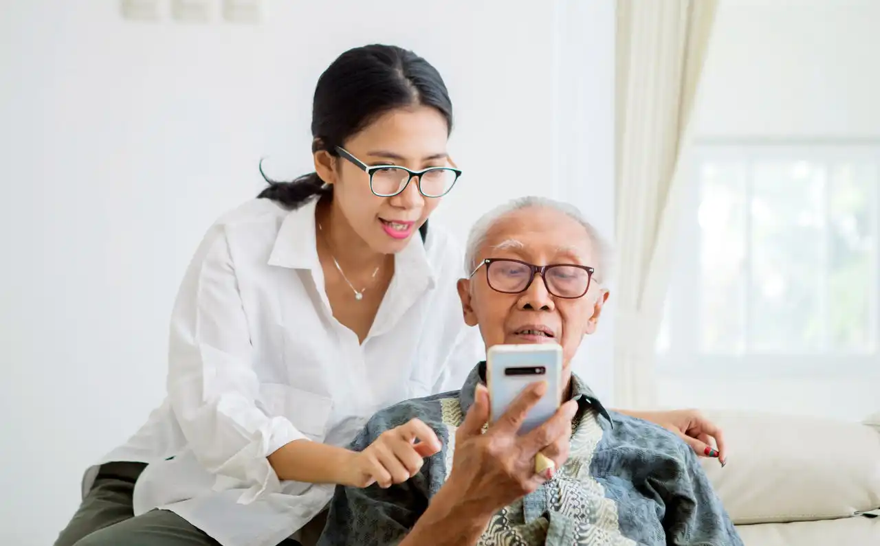 Two people looking at something on a smart phone sitting on the couch