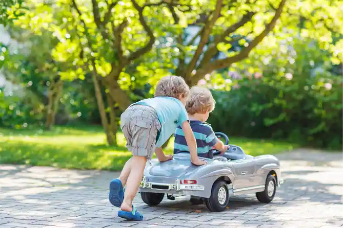 Boys play with ride on electric car outside