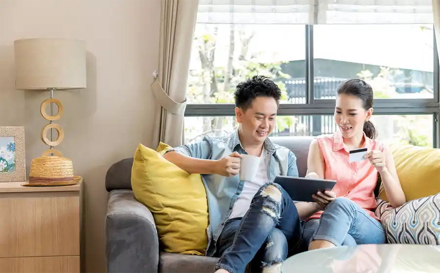Two people sitting on a couch with a card online shopping