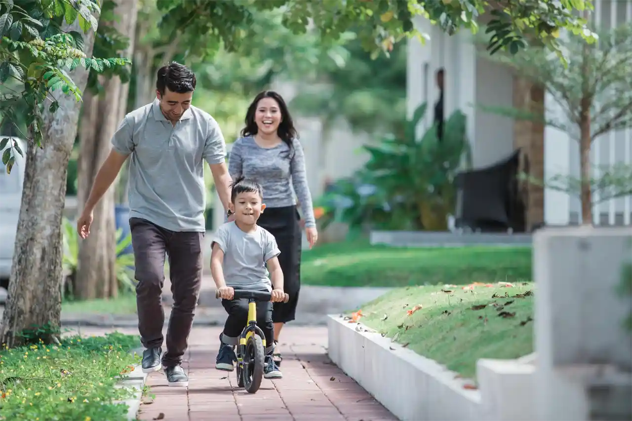 Parents outside with child on push bike learning to ride