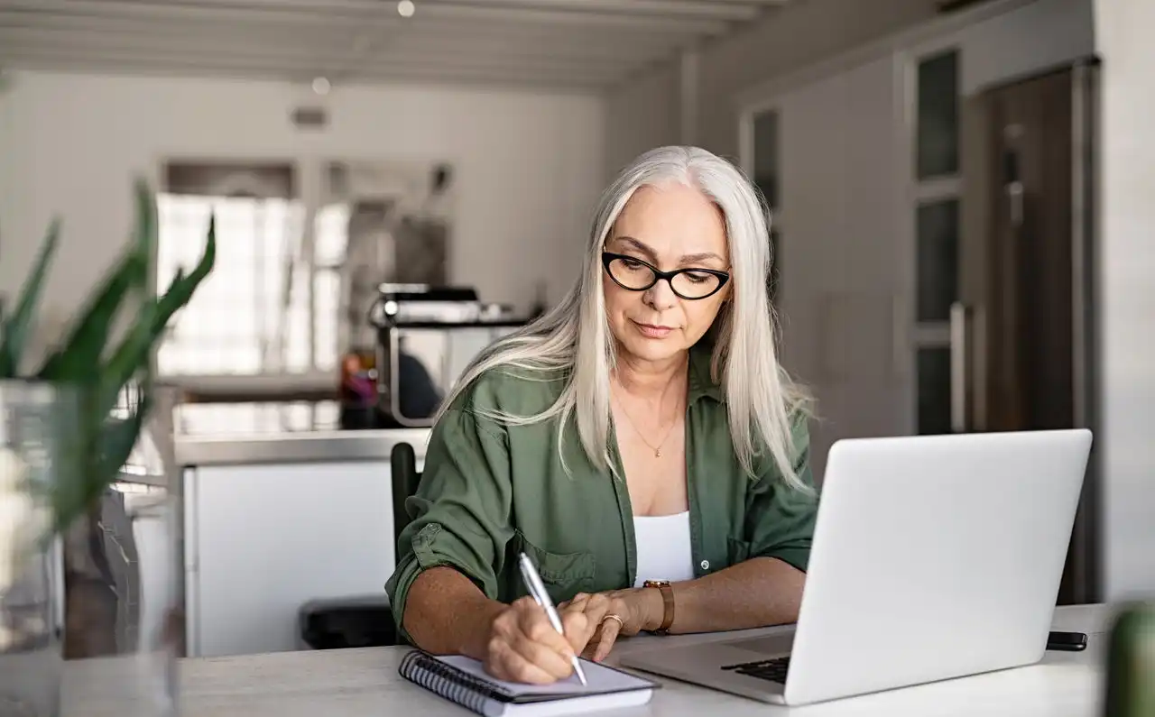 Person siting at a table with a laptop taking notes