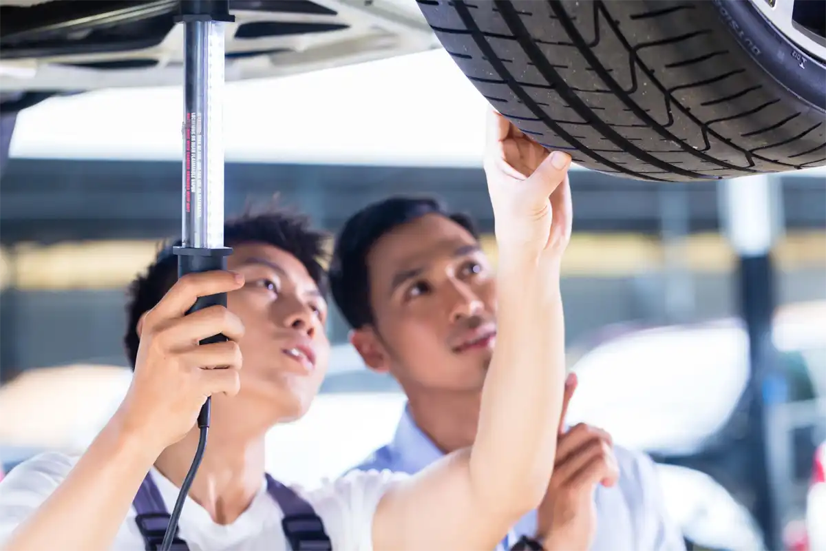 Mechanic and Customer inspecting tyres of car on a hoist