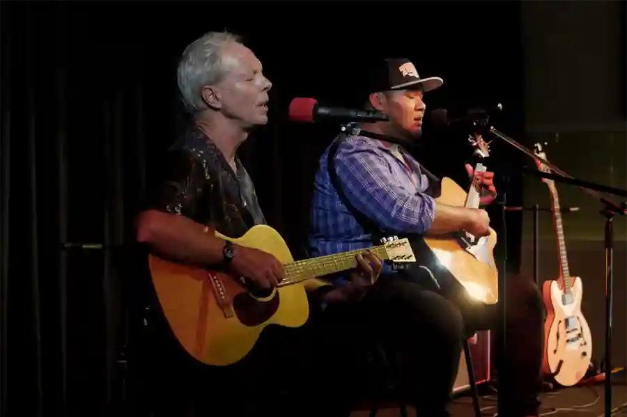 Two people performing with guitars in hand