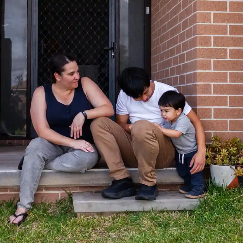 Parents sitting on the doorstep next to their child standing on the step below