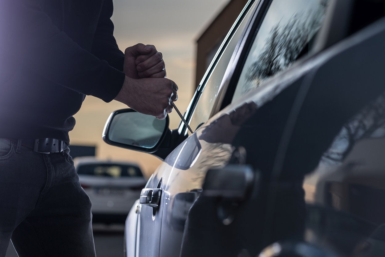 Auto thief in black balaclava trying to break into car with screwdriver. Car thief, car theft; Shutterstock ID 571866181; purchase_order: 1293 Content; job: Blog Images; client: Lana Monteleone; other: 