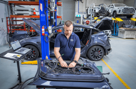 Photo of a person in NRMA uniform, working on part of a car.
