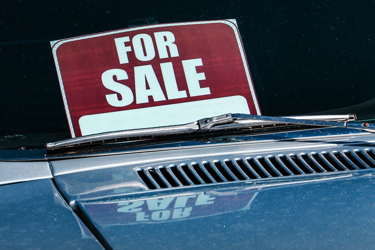 Photo of a car windshield with a red For Sale sign under the wiper.