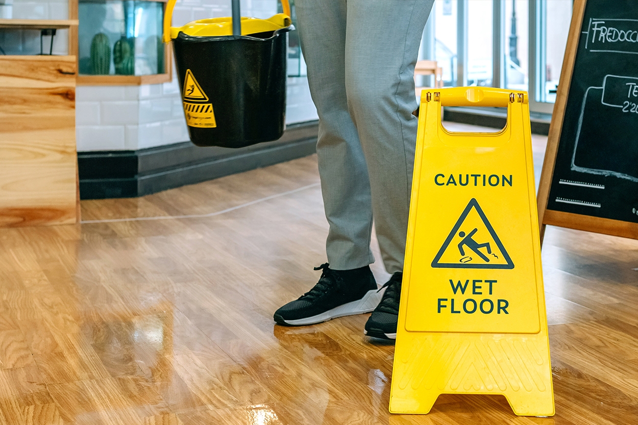 A yellow caution sign in a restaurant advises patrons of a wet floor